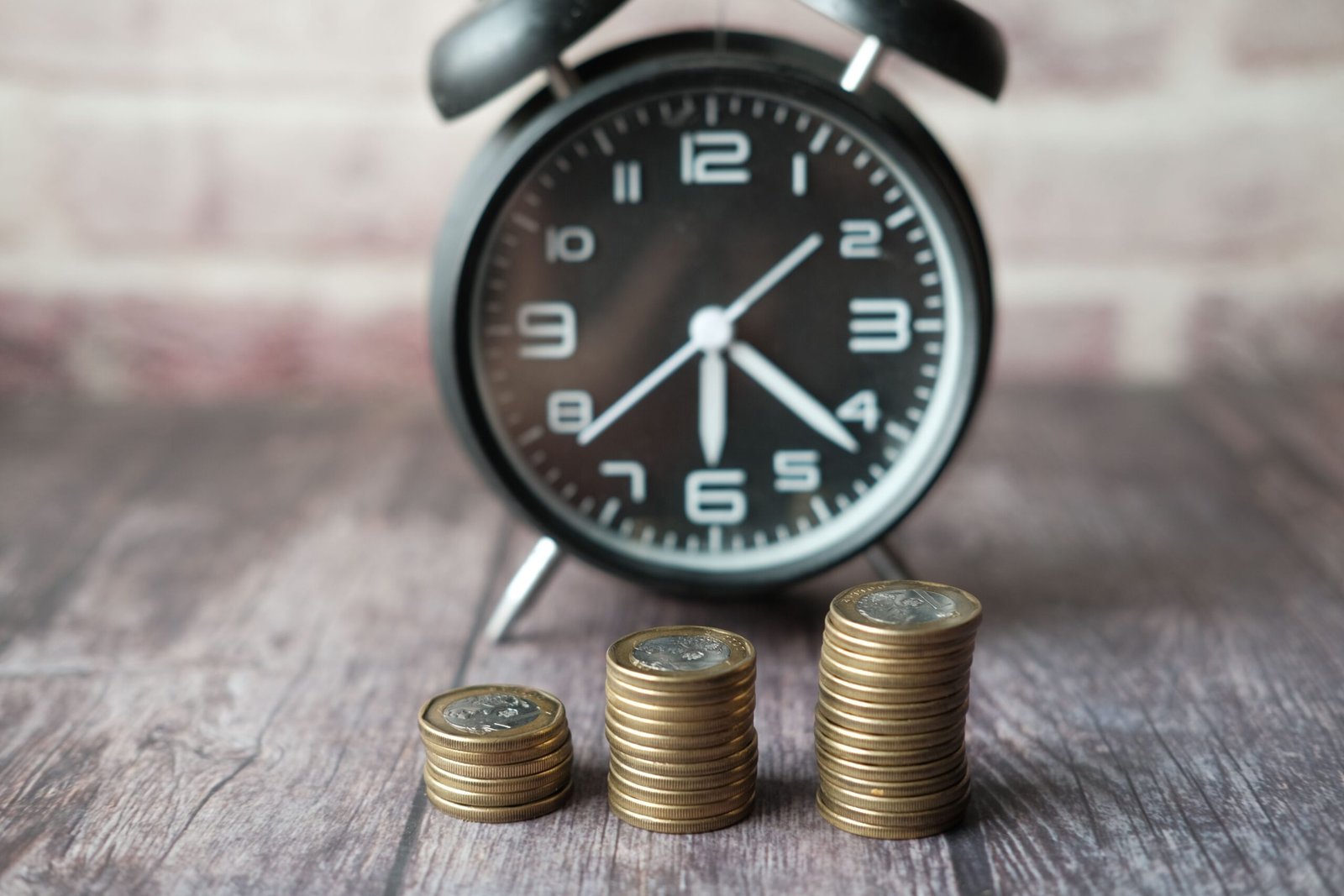 Alarm clock behind three stacks of coins