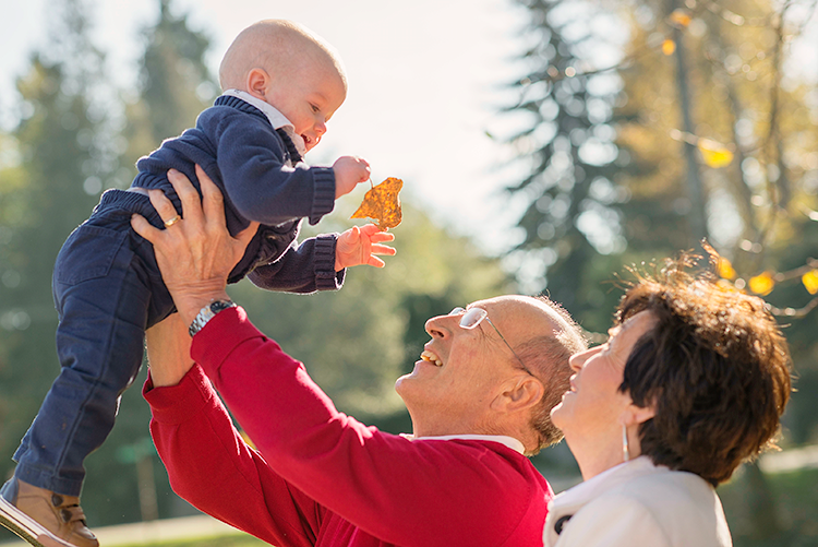Grandparents lifting their grandchild outdoors
